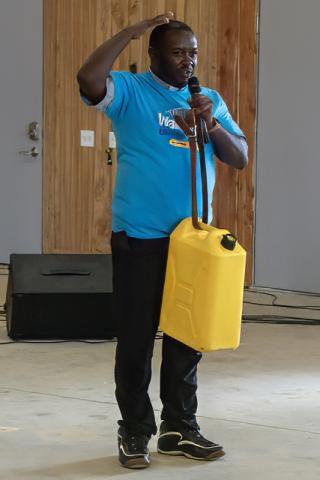 Father Joseph explaining how women carry the heavy water jugs. Photo by Patrick Hurley