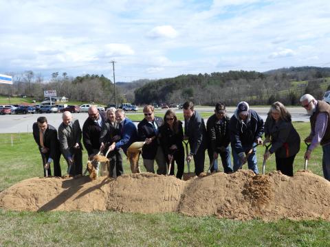 group of people shoveling dirt to symbolically begin construction on a highway