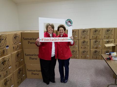 Operation Christmas Child Area Coordinator Amie Winstead and drop-off team leader Holly Simmons pose for a picture with filled boxes ready to ship.