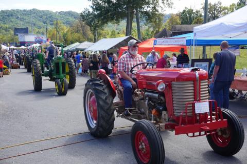 An antique tractor in a parade at a festival