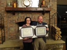 Man and a woman holding framed diplomas..