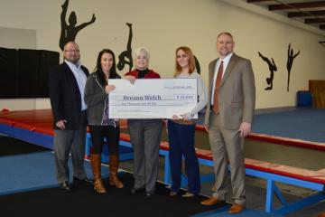 Breann Welch (second from left) of Sweet Southern Tumbling receives a small business loan check from Clinch Powell.